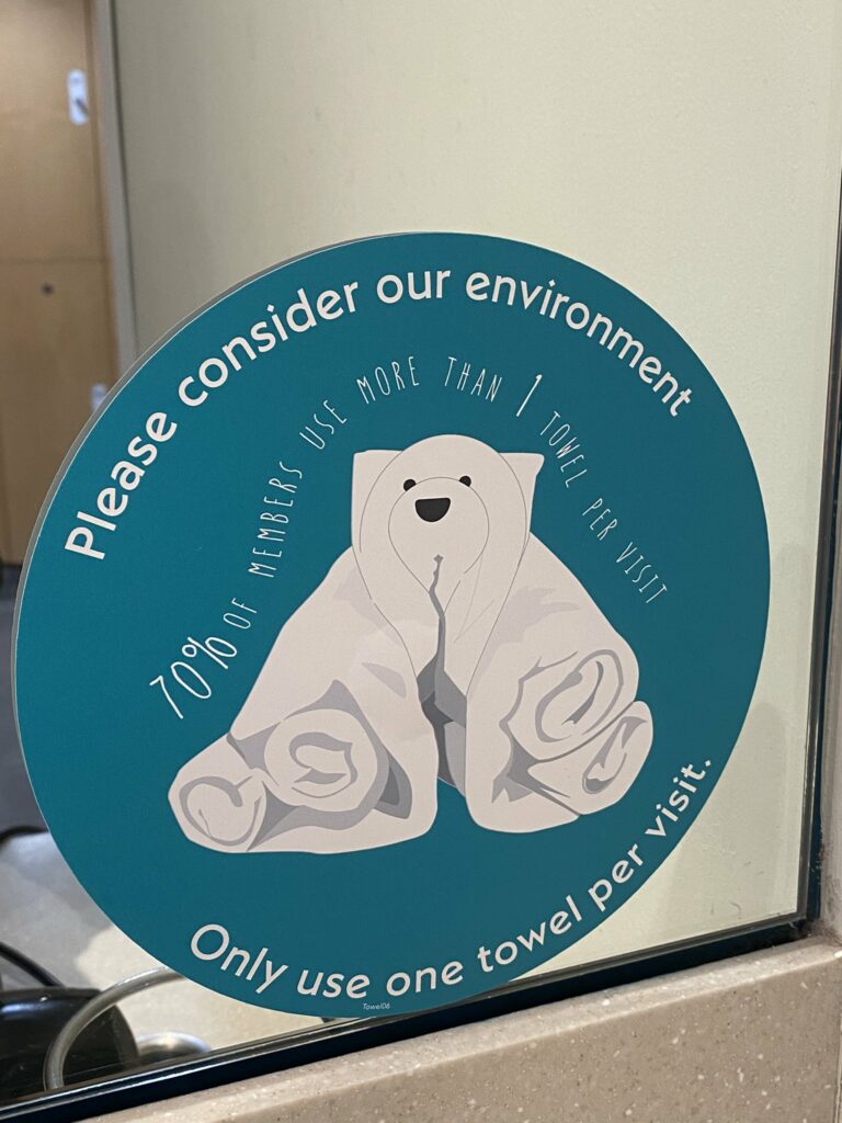 Image of a sticker on a mirror in a gym locker room that reads: Please consider our environment. 70% of members use more than 1 towel per visit. Only use one towel per visit.