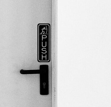 Push sign above door handle with an icon showing a figure pushing